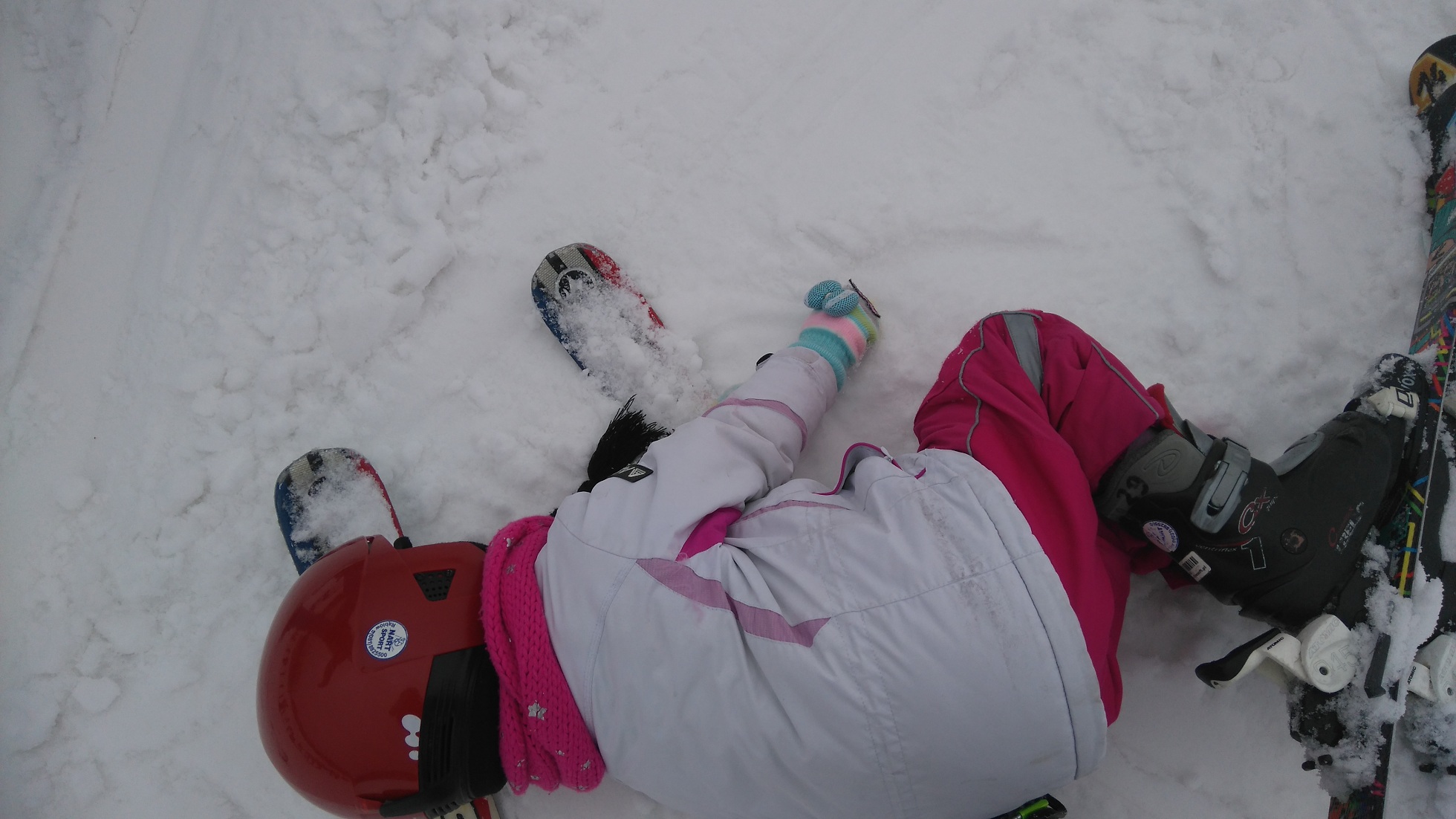 dziecko leży na śniegu w stroju narciarskim