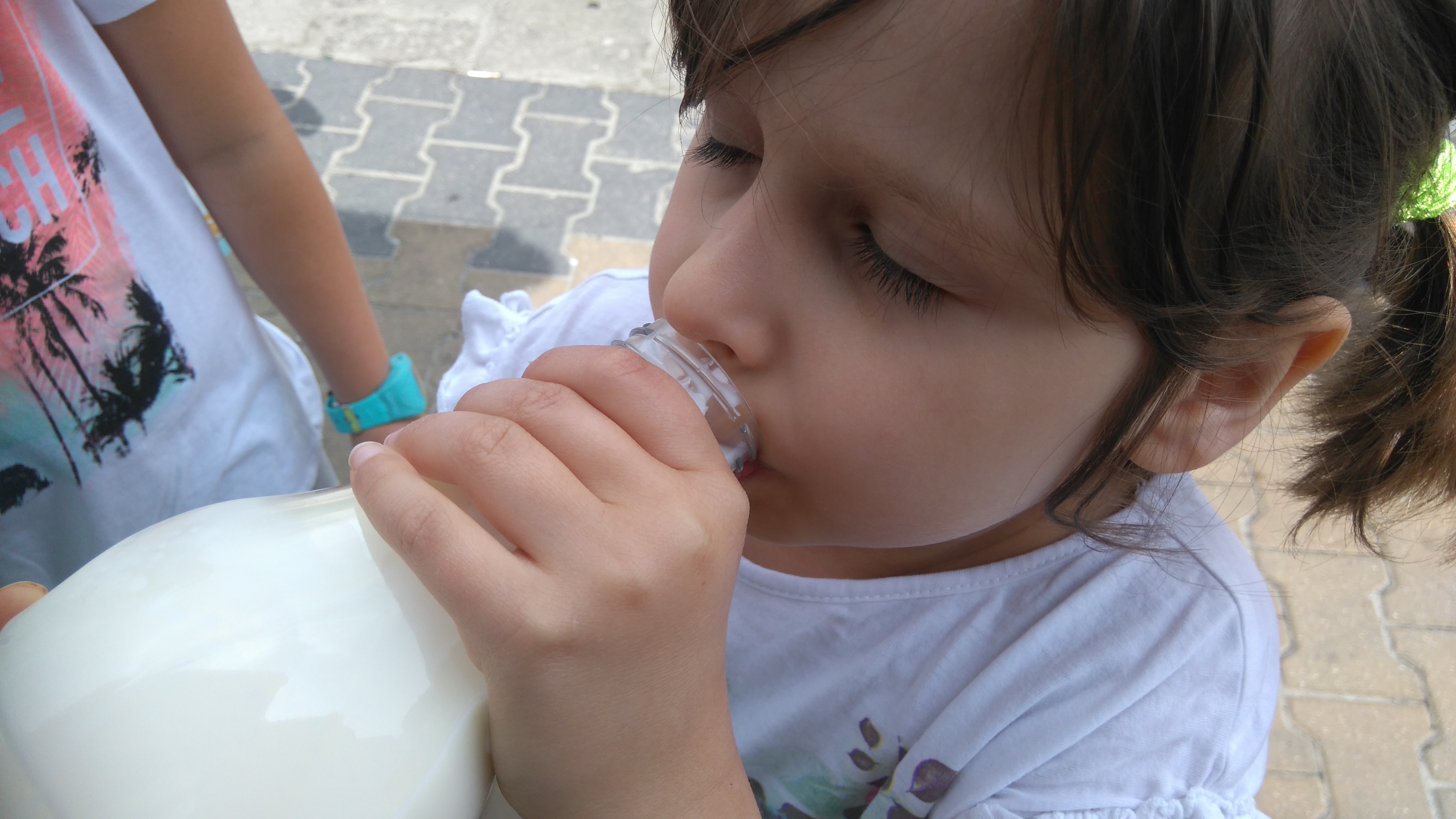 Dziewczynka pije mleko prosto z butelki