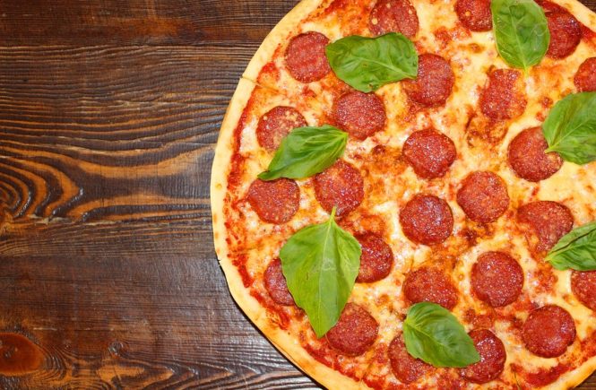 pizza na cienkim cieście z salami i listkami bazylii